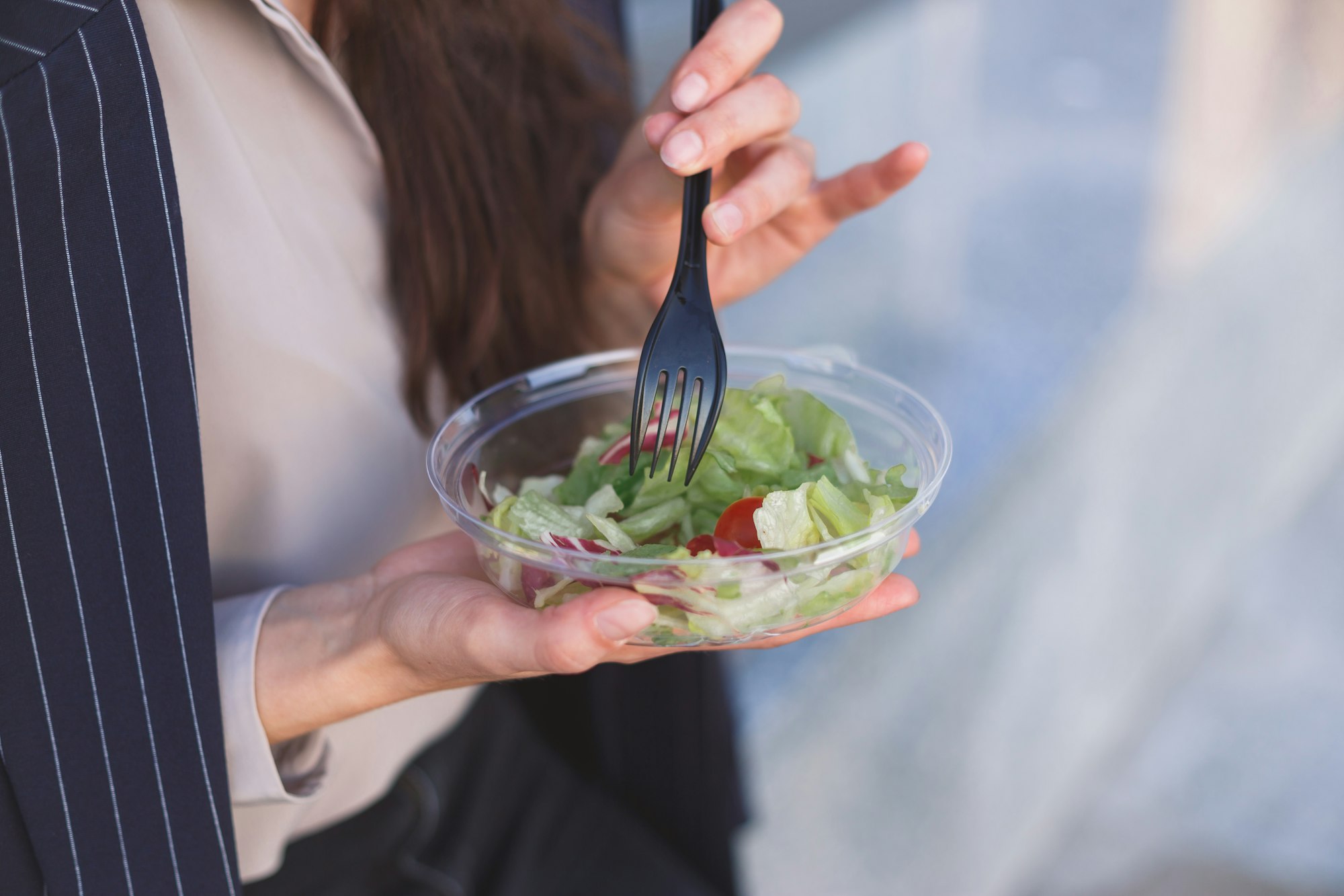 Office worker eats salad sitting outdoor